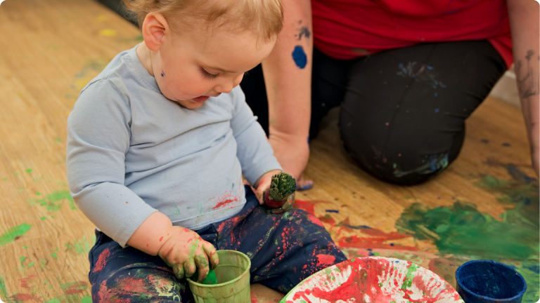 Baby playing with paint in the Perham Down Nursery